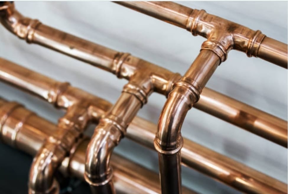 Close-up of copper plumbing pipes and fittings against a white background